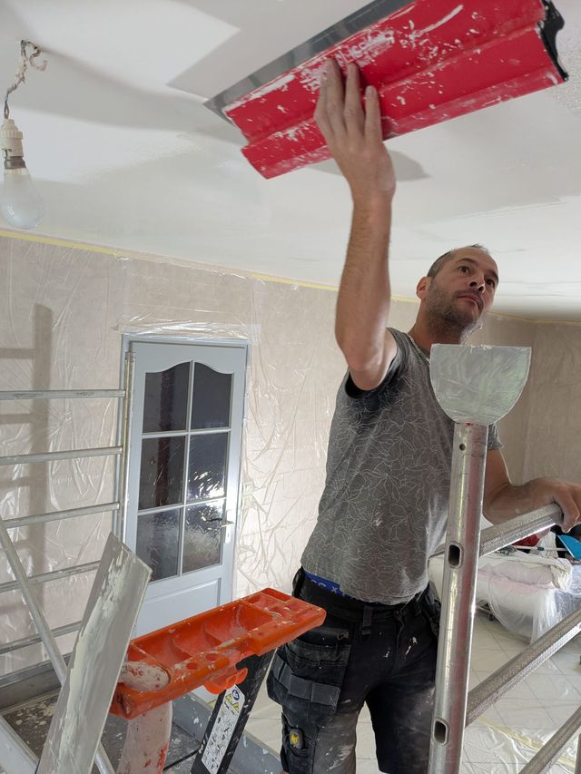 Christophe Léauté applique l'enduit au plafond à la lisseuse