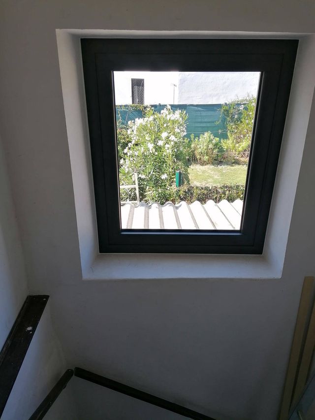 Fenêtre gris anthracite dans un tableau enduit, en haut d'escalier