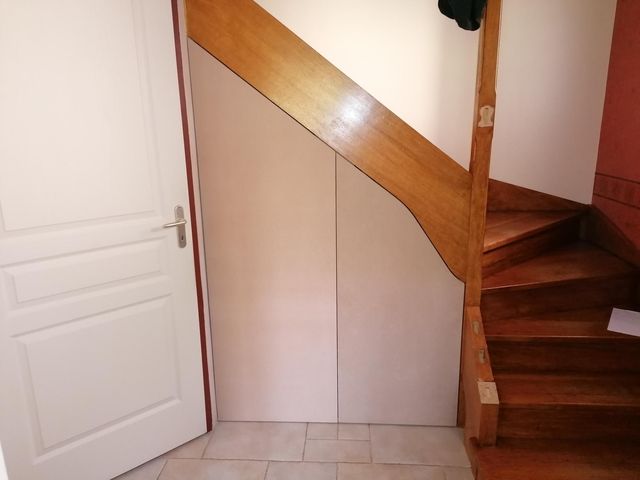 Placard à panneaux coulissants sous un escalier tournant en bois