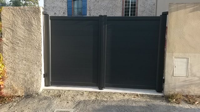 Portail battant en aluminium gris anthracite entre deux piliers