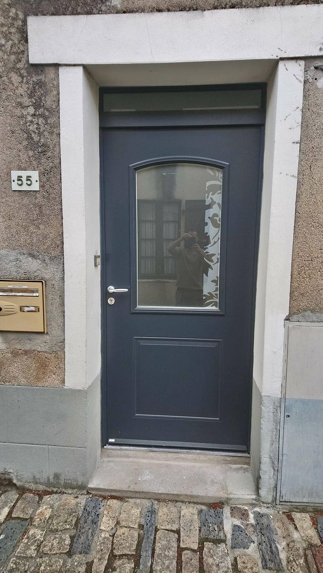 Porte d'entrée gris anthracite à vitrage cintré dans un encadrement en pierre, à Oudon