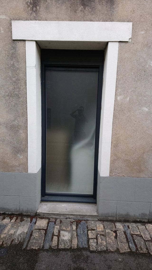Porte de service vitrée gris anthracite dans un encadrement en pierre, à Oudon