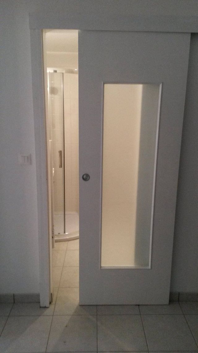 Porte à galandage blanche vitrée ouverte sur une salle d'eau