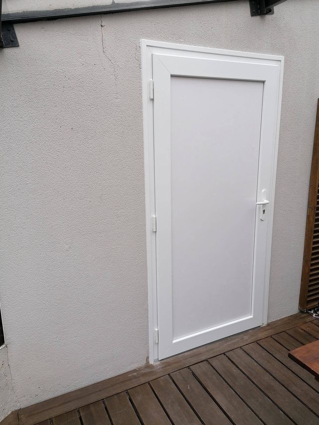 Porte de service blanche posée sur une terrasse bois