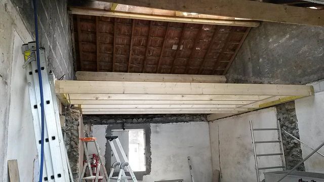 Pose de solives pour un plancher d'étage dans une maison en pierre